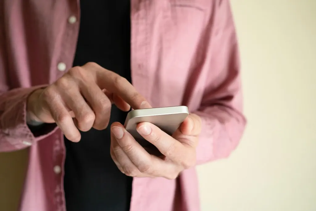 A person in a pink shirt scrolling through text messages on a smartphone